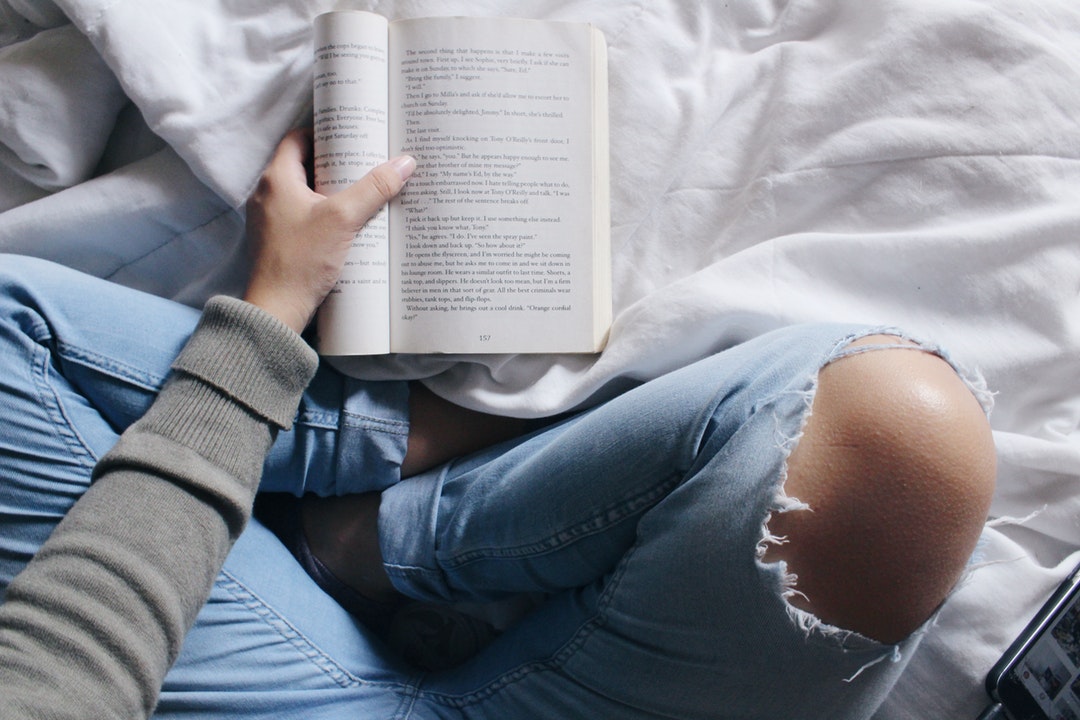 person on bed reading book